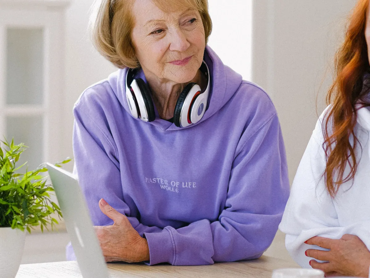 Une femme senior souriante, un ordinateur portable et une tasse de café sur la table