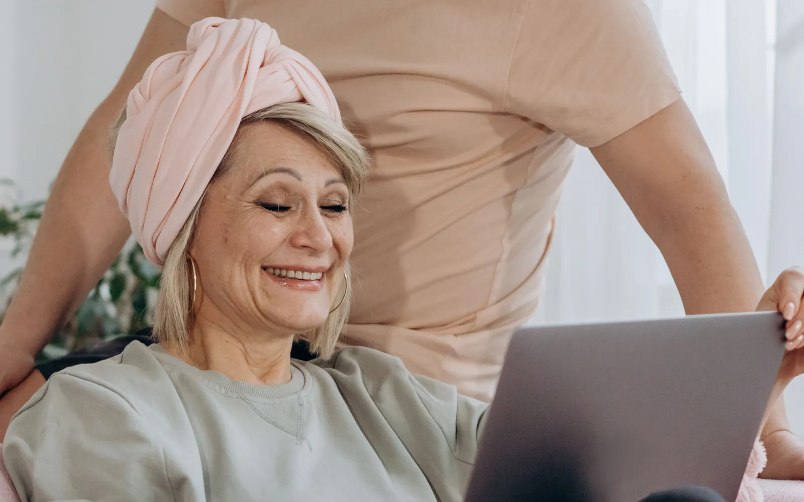 Un couple de seniors souriant, utilisant ensemble un ordinateur portable dans leur salon